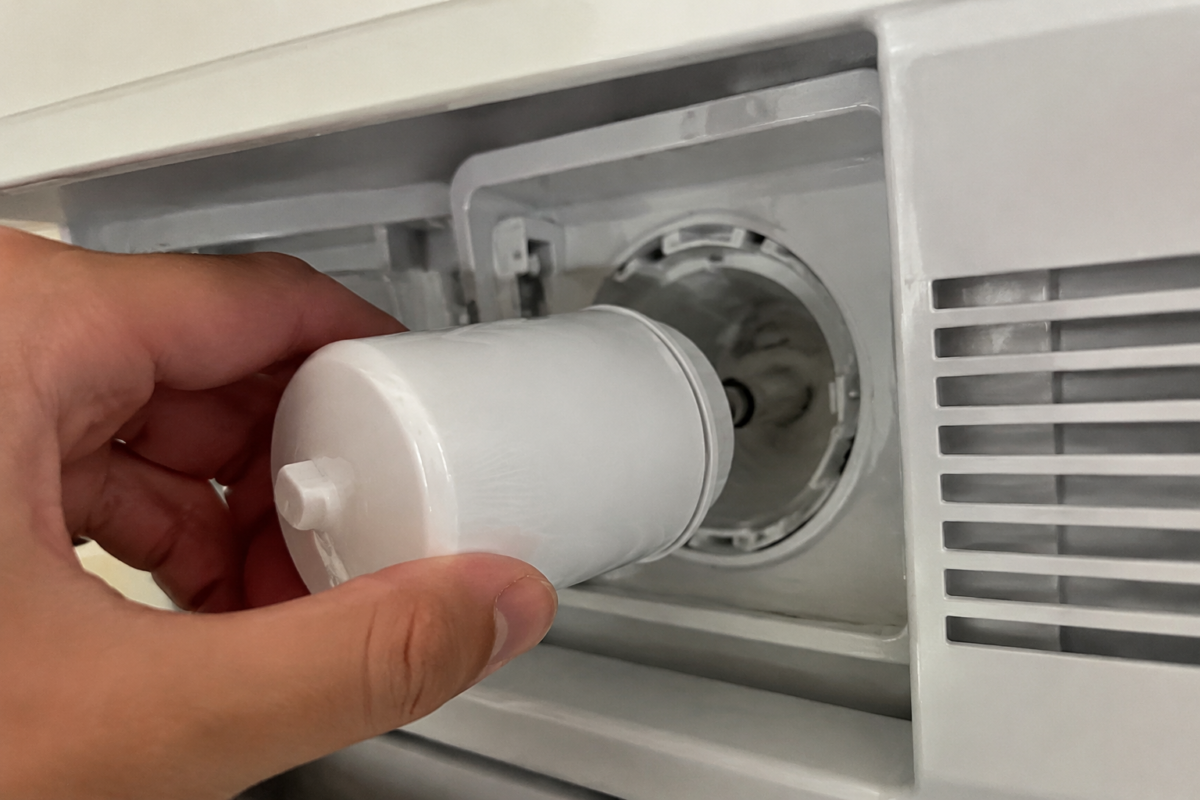 GE refrigerator water filter bypass plug being inserted into the filter head slot