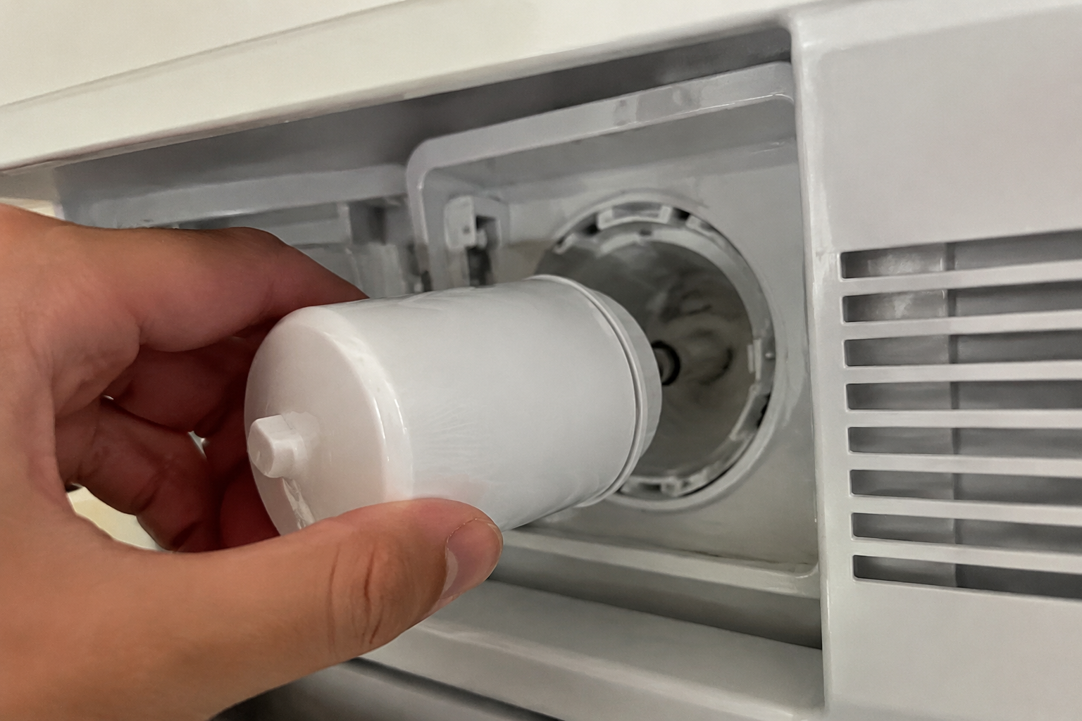 GE refrigerator water filter bypass plug being inserted into the filter head slot