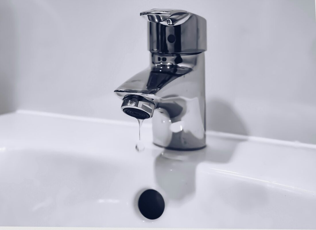 Limescale buildup on a chrome bathroom faucet caused by hard water