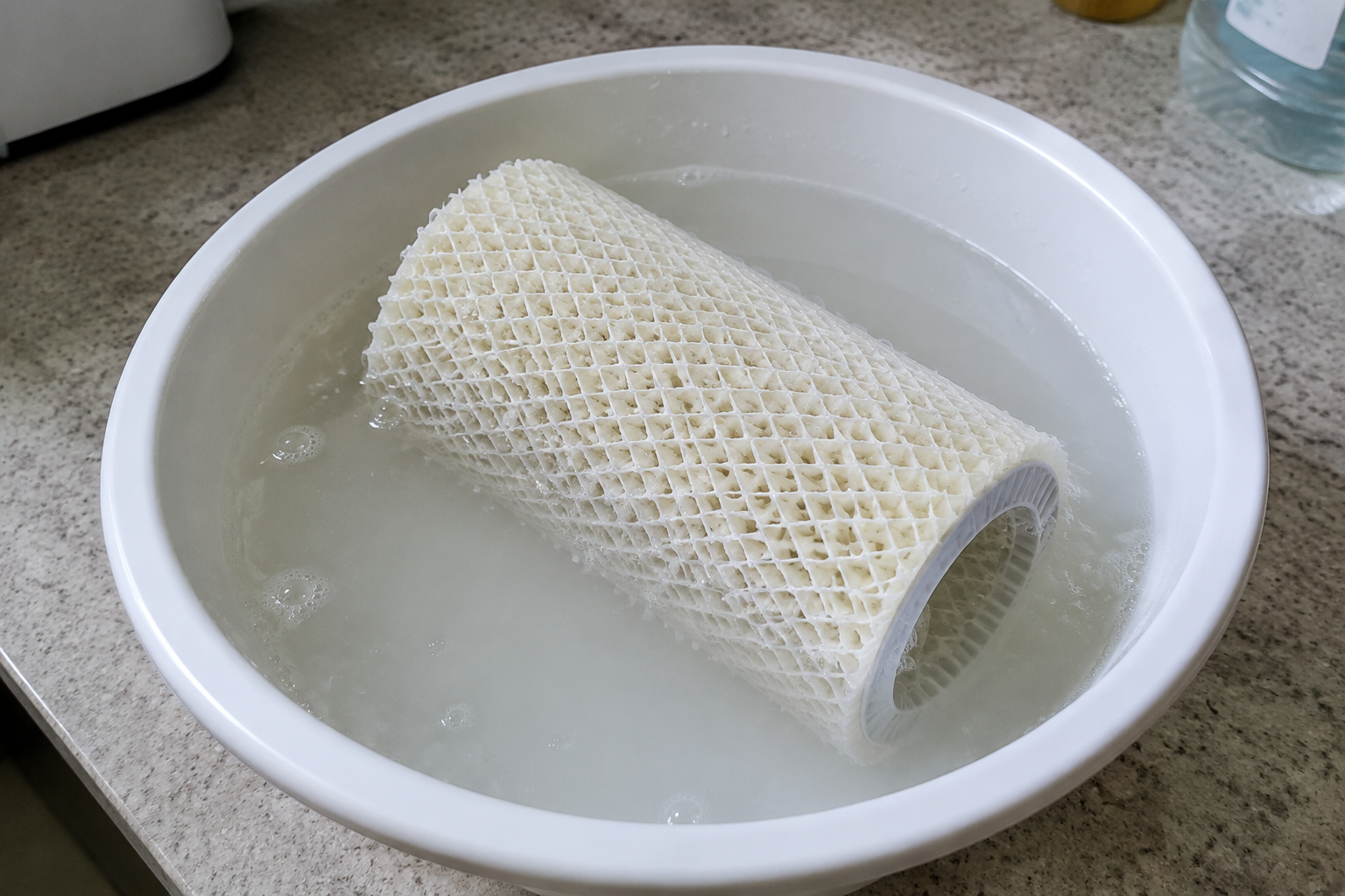 Evaporative humidifier wick filter soaking in a vinegar solution in a basin