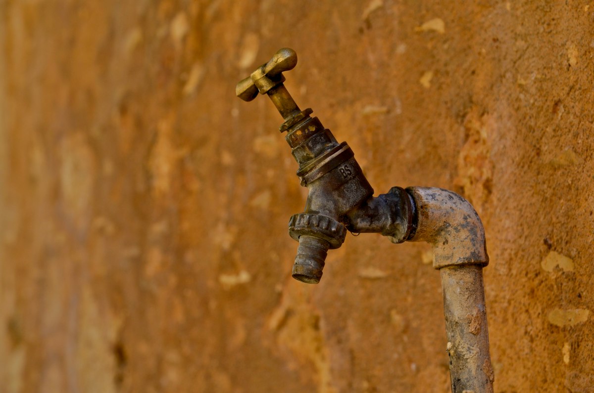 Orange rusty water running from a bathtub faucet