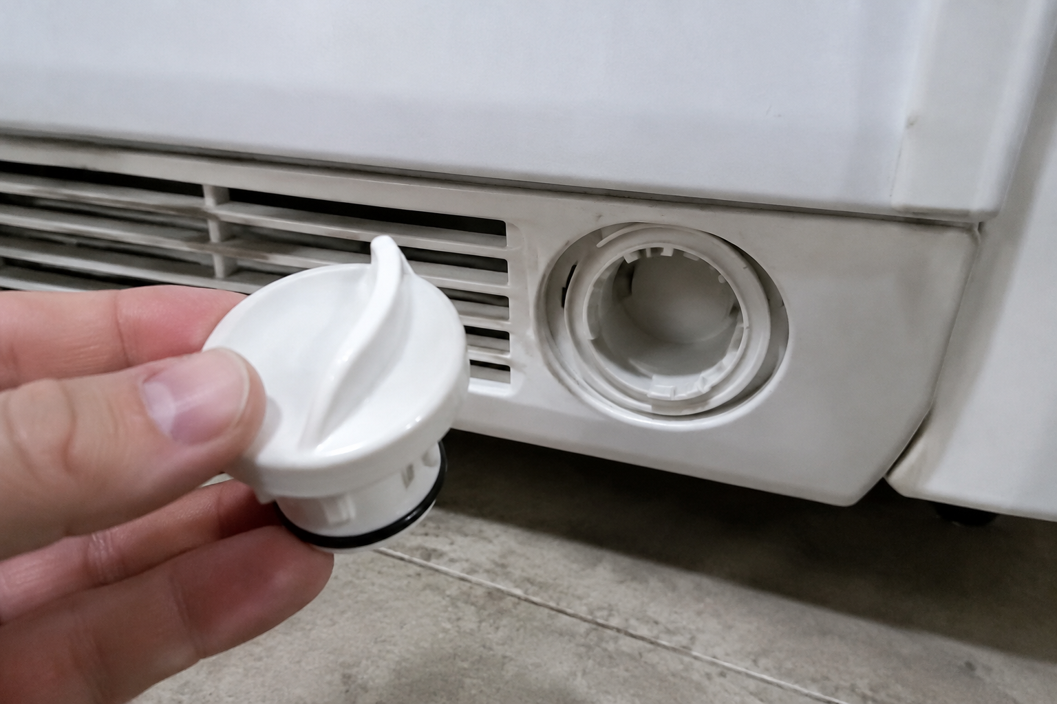 Generic refrigerator water filter bypass plug held next to an open filter bayonet slot