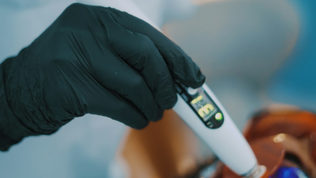 Digital TDS meter measuring total dissolved solids in a glass of water